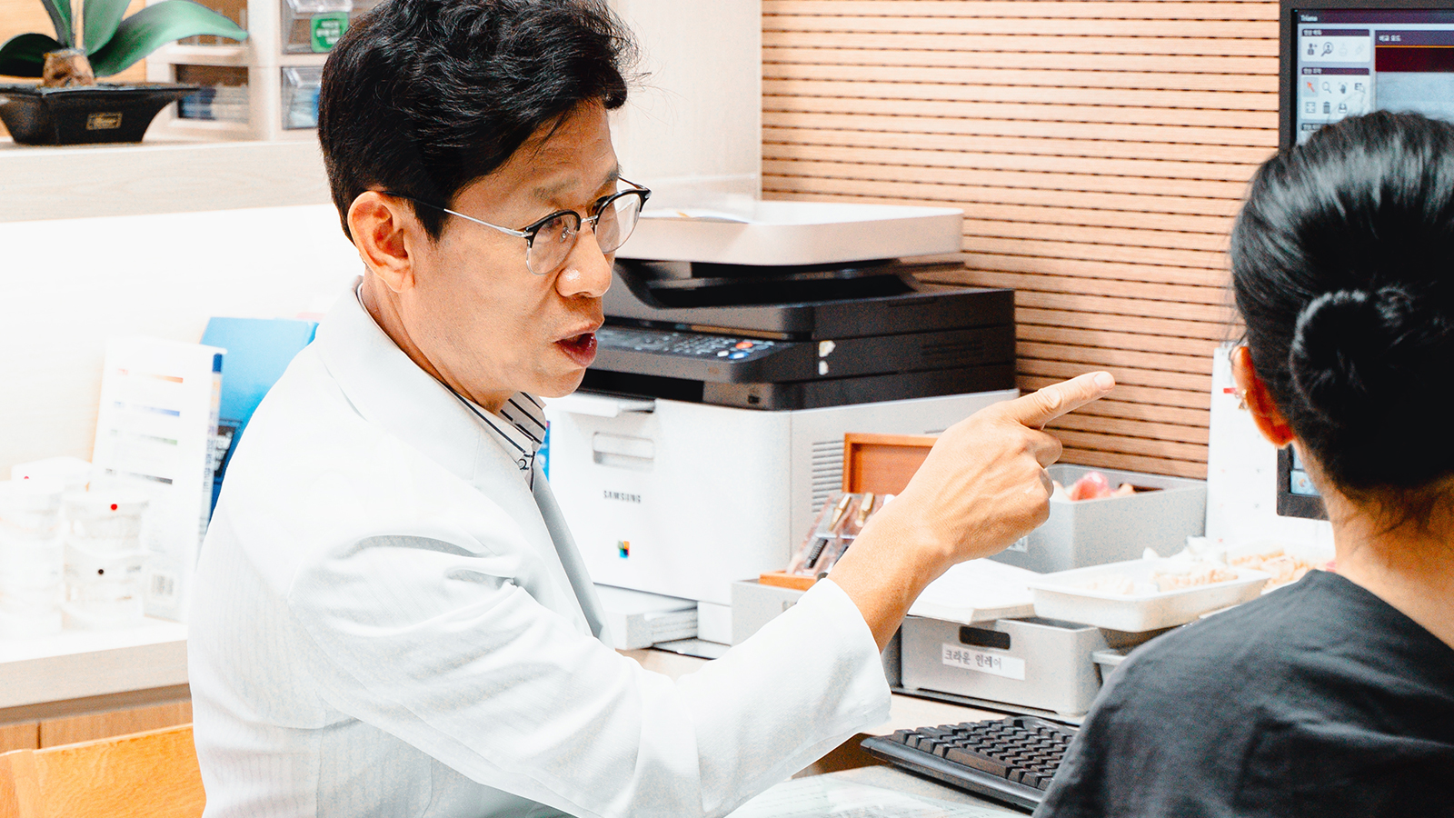 교정 발치 여부를 모니터 화면을 가리키며 환자에게 설명하는 원장
